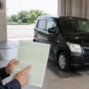 車検証で型式を確認する日本人男性と黒いワゴンR